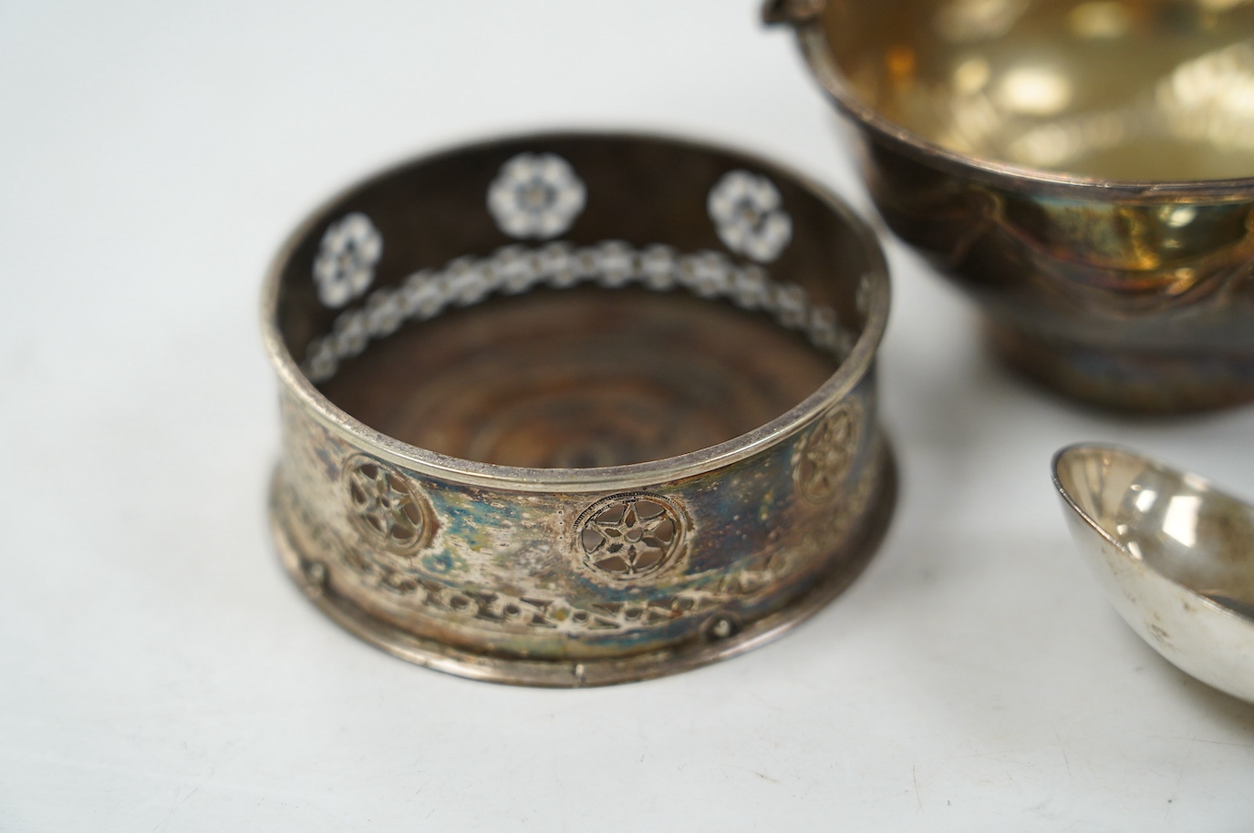 A George III silver small epergne basket, London, 1800, diameter 80mm, a large William IV silver caddy spoon and an Old Sheffield plate sauce bottle coaster. Condition - fair